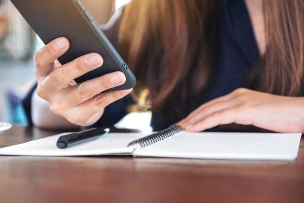 Foto sezione centrale di una donna d'affari che usa il telefono mentre è seduta alla scrivania in ufficio