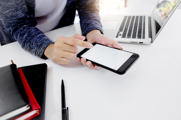 midsection of businesswoman using smart phone at desk