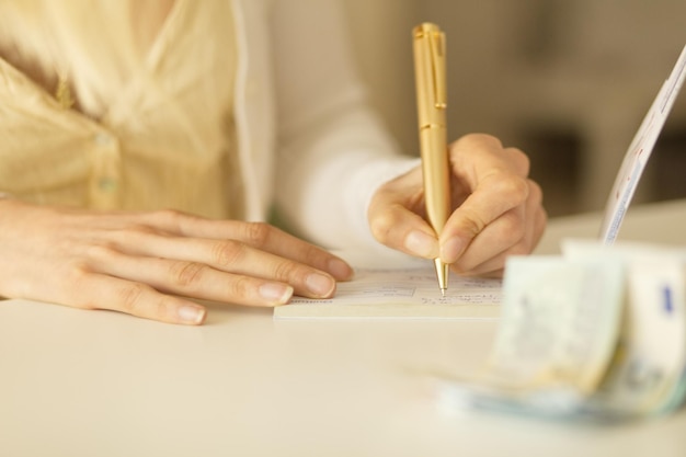 Midsection of businesswoman writing on check in office