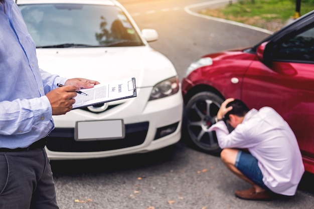 Photo midsection of car insurance agent making note by sad man on road