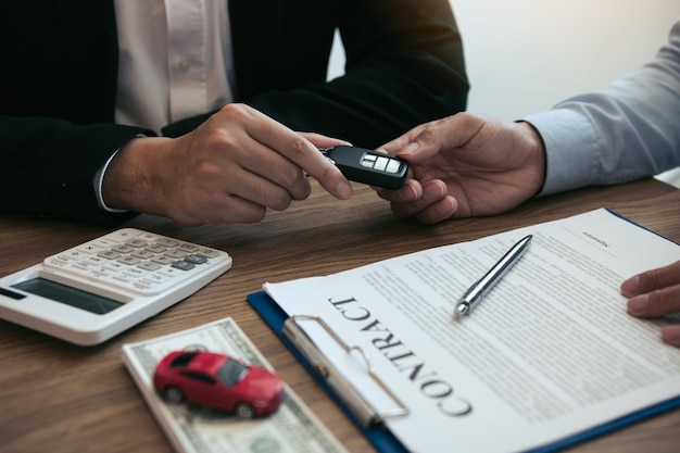 カーセールスマンが顧客に車の鍵を渡すミッドセクション