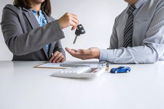 Photo midsection of car saleswoman giving car key to customer