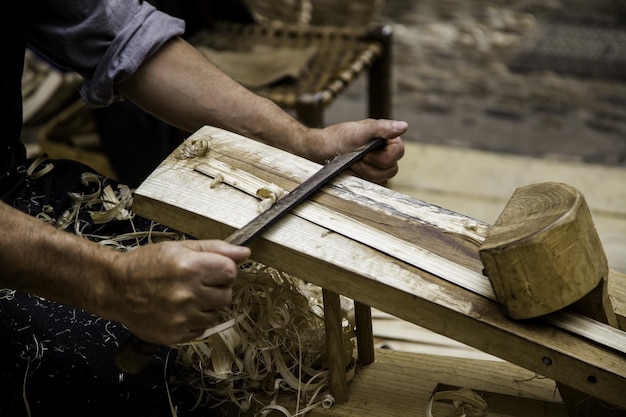 Photo midsection of carpenter shaving wood in workshop