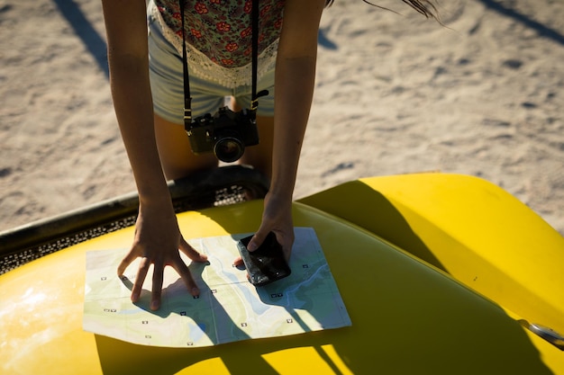 Photo midsection of caucasian woman reading roadmap on beach buggy by the sea