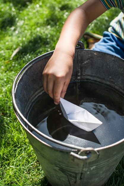 Foto sezione centrale di un bambino che tiene una barca di carta in acqua