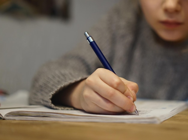 midsection of child writing on book at table