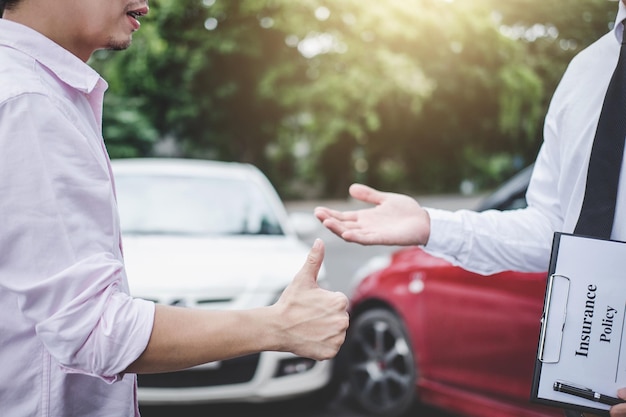 midsection of client showing thumbs up to agent while standing against cars on road