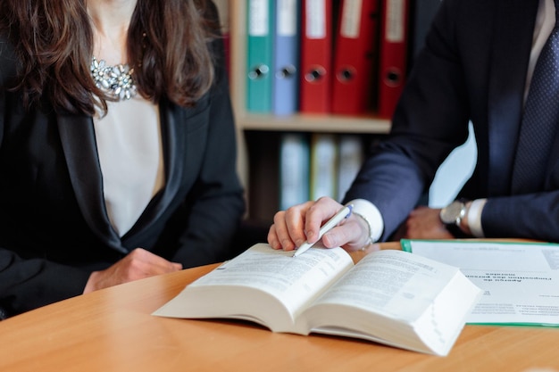 Foto parte centrale di colleghi che discutono su un libro sul tavolo in ufficio