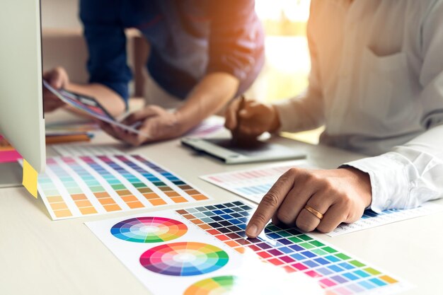 Photo midsection of colleagues discussing color swatch on desk in office