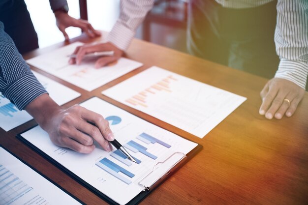 Photo midsection of colleagues discussing over graph in office