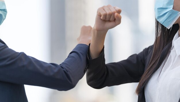 Midsection of colleagues doing elbow bump in office