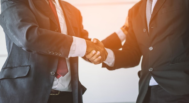 midsection of colleagues shaking hands at office