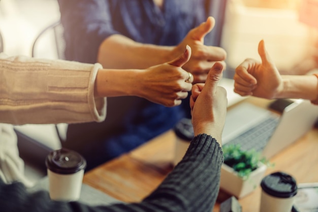 Photo midsection of colleagues showing thumbs ups in office