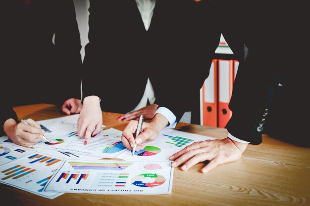 Photo midsection of colleagues working over graph at table in office