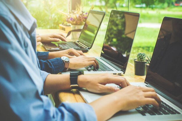 Midsection of colleagues working on laptop at table