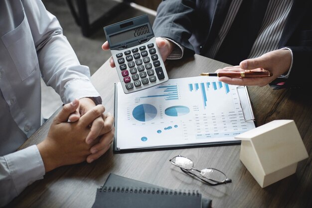 Photo midsection of colleagues working with calculator and graphs on desk