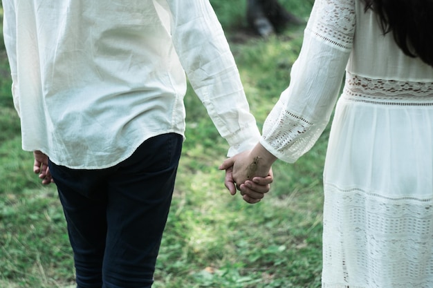 midsection of couple holding hands on field