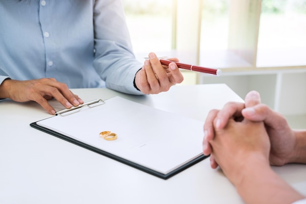 Photo midsection of couple signing divorce paper on desk