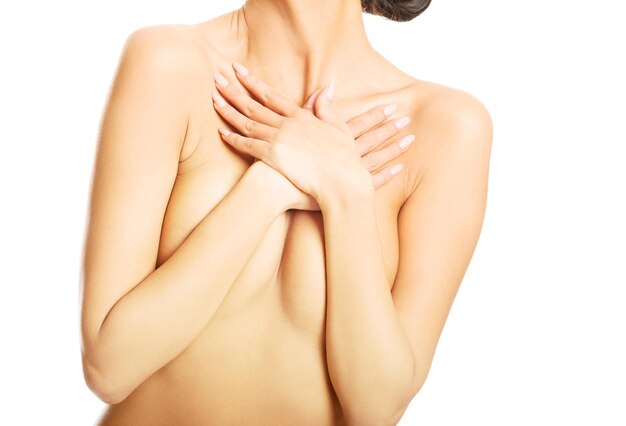 Midsection of covering breast while standing against white background