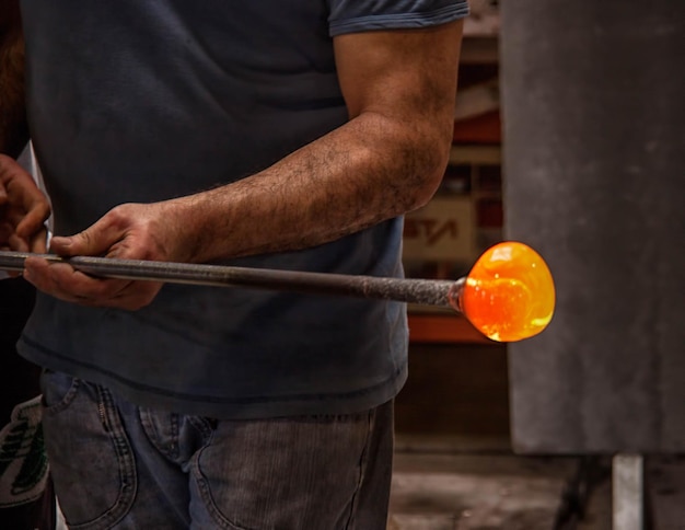 Foto sezione centrale di artigiani che modellano il vetro in officina