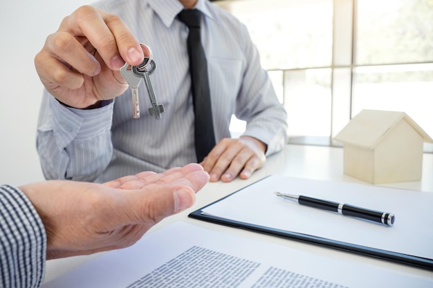 Photo midsection of customer receiving keys from insurance agent while sitting in office