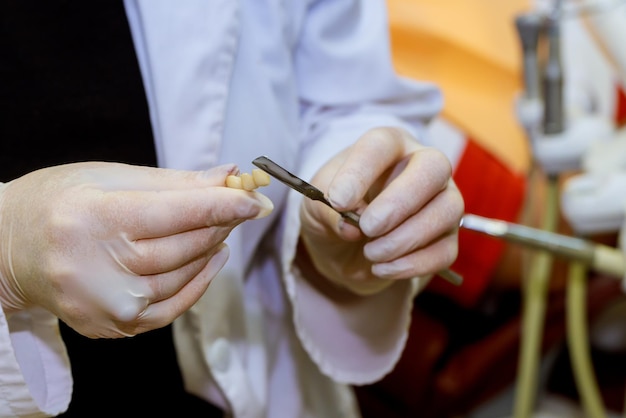 Photo midsection of dentist holding dentures at clinic