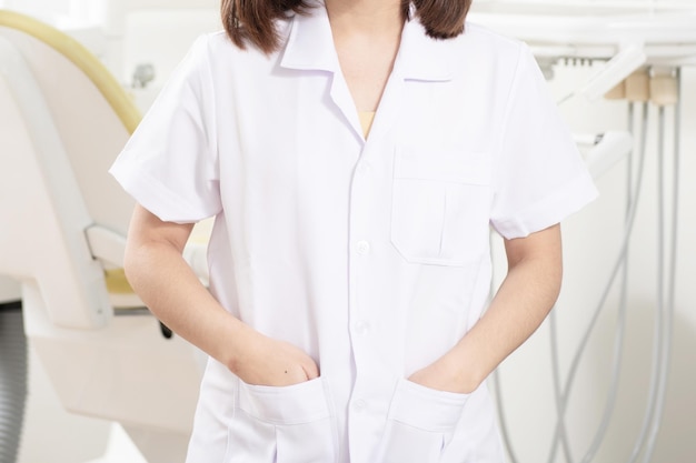 Midsection of dentist with hands in pockets standing at clinic