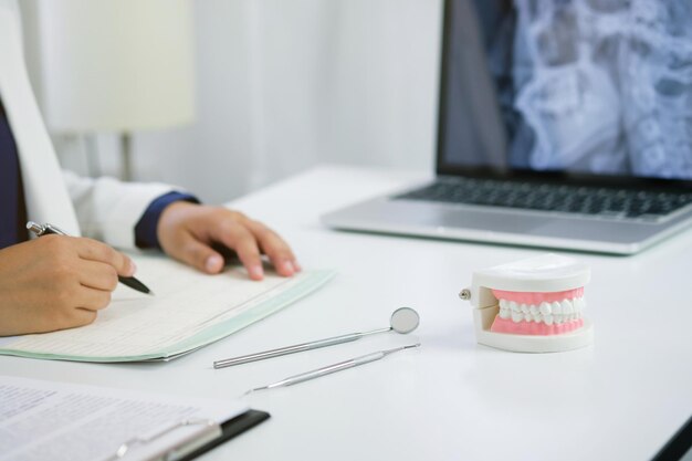 Midsection of dentist writing in paper on table