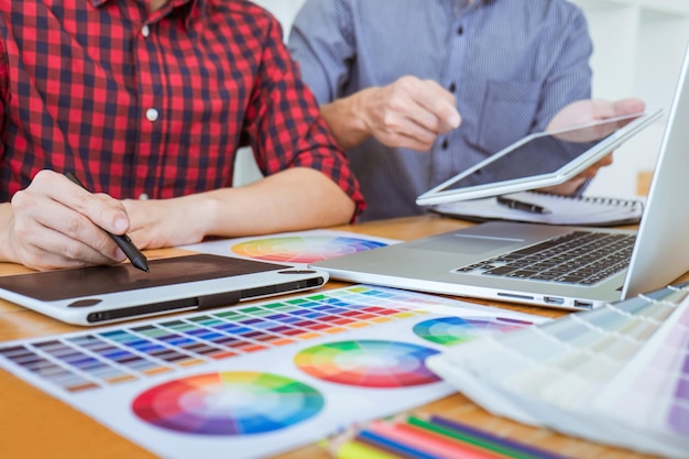 Foto sezione centrale di professionisti del design con campioni di colore e laptop che lavorano sulla scrivania dell'ufficio