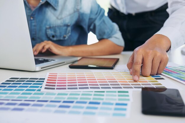 Photo midsection of design professionals with laptop and color swatches on office desk