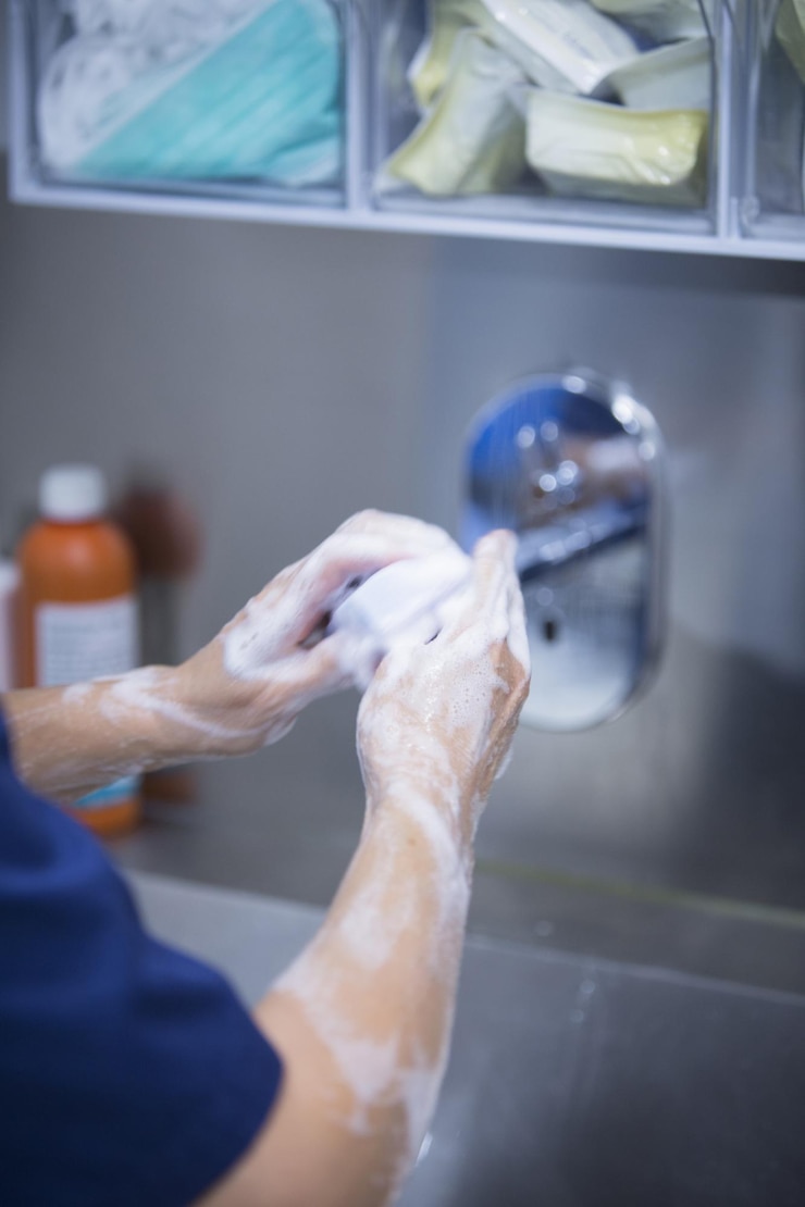 Photo midsection of doctor cleaning hands with soap in hospital