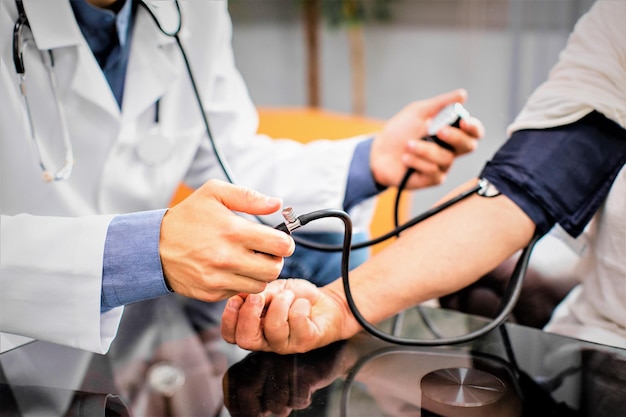 Midsection of doctor examining patient blood pressure with gauge in hospital