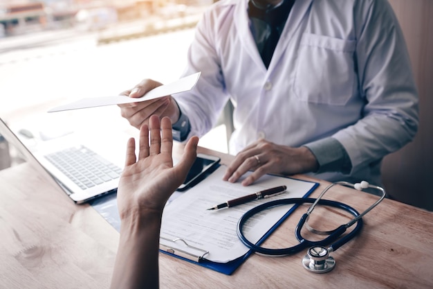 Midsection of doctor giving prescription to patient while sitting on table