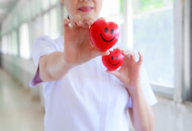 Photo midsection of doctor holding heart shape while standing at hospital