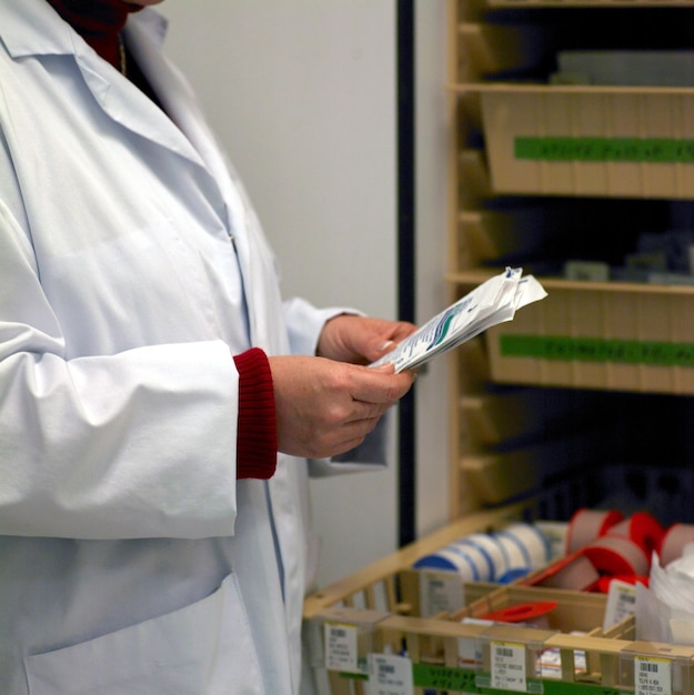 Photo midsection of doctor holding medical papers by drawers