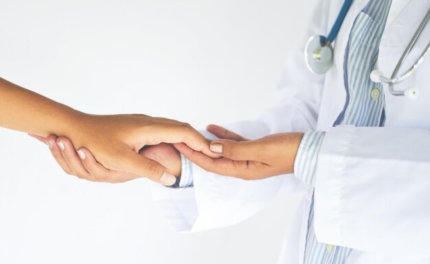 Midsection of doctor holding patient hand against white background