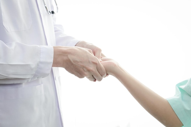 Midsection of doctor holding patient hands in hospital