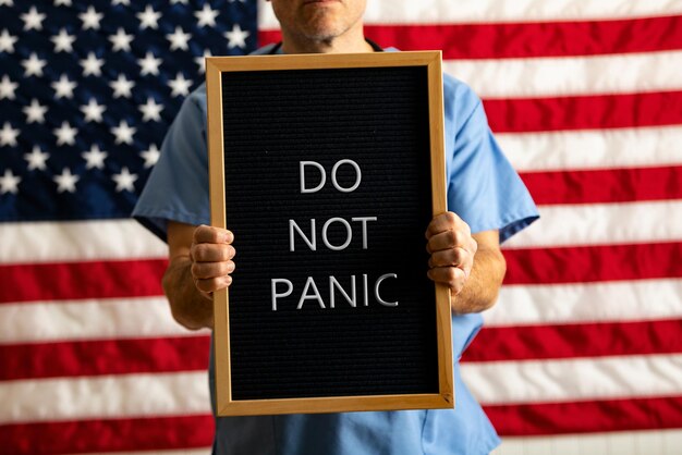 Midsection of doctor holding sign board against american flag
