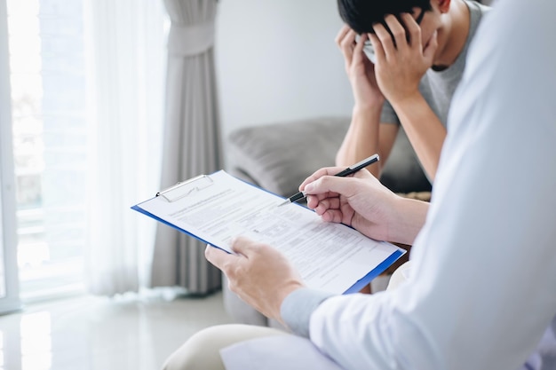 Midsection of doctor reading medical report while sitting with patient in hospital