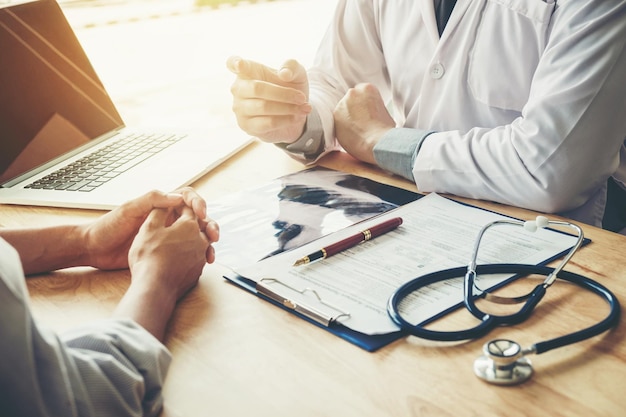 Midsection of doctor sitting at desk with patient