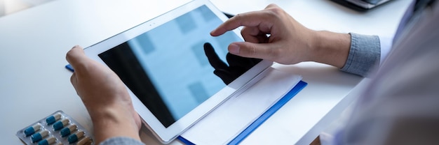 Photo midsection of doctor using digital tablet on table