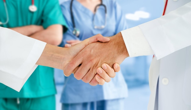 Midsection of doctors shaking hands at clinic