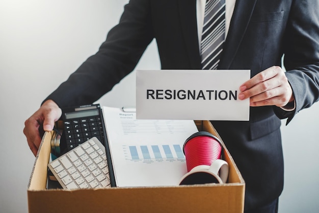 Midsection of employee holding box with resignation