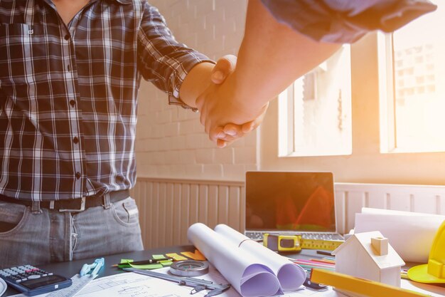 Midsection of engineers shaking hands over table in office