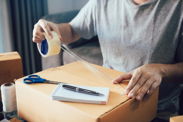 Midsection of entrepreneur packing cardboard box at home