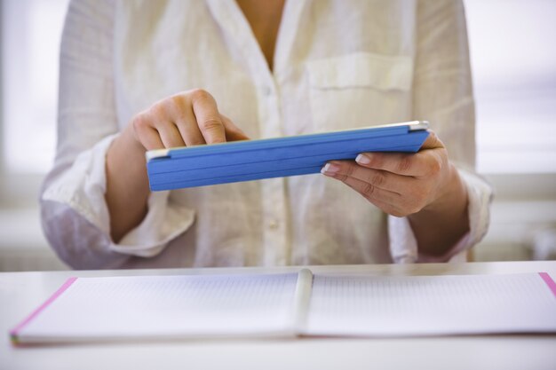 Midsection of executive using digital tablet at office