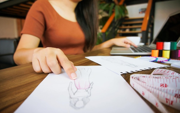 Photo midsection of fashion designer looking at design while sitting on table