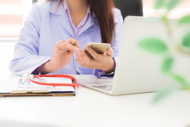 Foto sezione centrale di una dottoressa che usa il telefono cellulare in ufficio