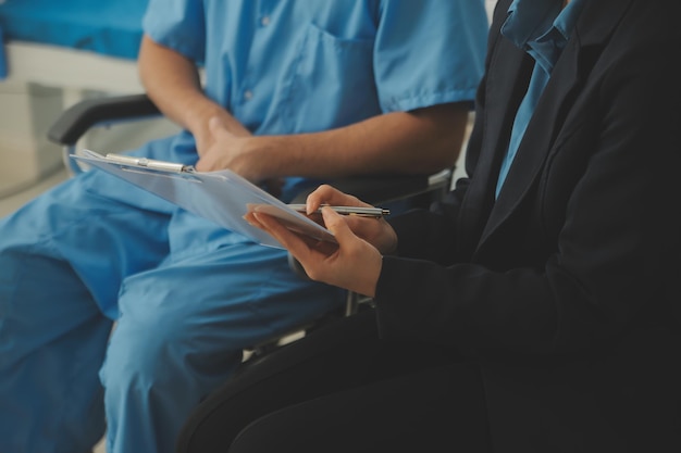 Midsection of female nurse checking blood pressure of woman sitting on wheelchair in clinic