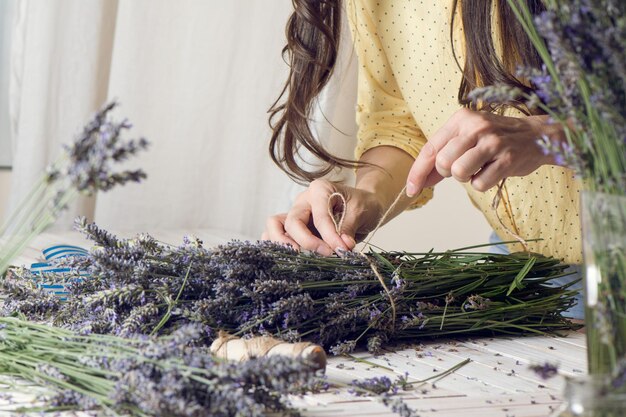 Foto sezione centrale del fioraio che organizza un mazzo di fiori di lavanda sul tavolo